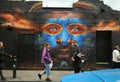 People on the streets of Brick Lane with famous graffiti, East London