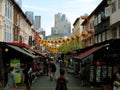 People strolling through a market on a street decorated with red and yellow lanterns in Singapore