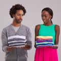 People, studio and pile of laundry in hand for neat, wash day or cleaning clothes together. Couple, thinking and unsure Royalty Free Stock Photo