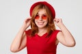 People, style and clothing concept. Happy cute young female in red hat, shades and t shirt, being glad to be photographed for fash Royalty Free Stock Photo