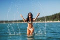 woman in bikini splashing sea water on beach Royalty Free Stock Photo