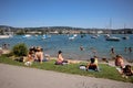 People sunbathe and enjoy by the Zurich lake. many boats and yachts on water. Clear blue city lake on summer Royalty Free Stock Photo