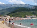 People sunbathe on the sandy beach and swim in the sea at the foot of the mountains