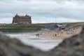 People surfing and swimming at Fistral Beach with the life guards watching and with The Headland Cornwall hotel in the background
