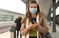 People with surgical mask using smartphone at train station Royalty Free Stock Photo