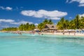 People swimming near white sand beach with umbrellas, bungalow bar and cocos palms, turquoise caribbean sea, Isla Mujeres island,