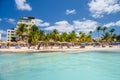 People swimming near white sand beach with umbrellas, bungalow bar and cocos palms, turquoise caribbean sea, Isla Mujeres island,