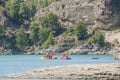 People swimming and relaxing on a lake with rocky shore. Sunny day on a lake with turquoise water. Summer vacations.