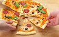 People take pizza slices with cheese, mushrooms, salami