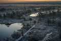 People taking pictures on wooden path, road in swamp on early winter morning