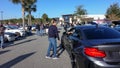 People talking at automobiles at a free to the public Cars and Coffee car show