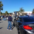 People talking at automobiles at a free to the public Cars and Coffee car show