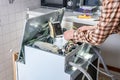 People in technician jobs. Appliance repair technician or handyman works on broken dishwasher in a kittchen. Laborer is changing Royalty Free Stock Photo