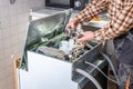 People in technician jobs. Appliance repair technician works on broken dishwasher in a kittchen. The technician shows the heating