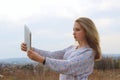 People, technology, communication concept. Young girl is studying remotely on a tablet outdoors.