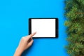 People and technology concept, close up of female hands pointing finger to tablet. blank screen on blue background, top view Royalty Free Stock Photo