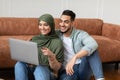 Happy muslim man and woman using laptop pointing at screen Royalty Free Stock Photo