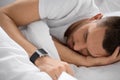 Close up of man with smart watch sleeping in bed