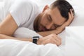 Close up of man with smart watch sleeping in bed