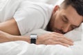 Close up of man with smart watch sleeping in bed