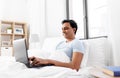 Happy indian man with laptop in bed at home Royalty Free Stock Photo