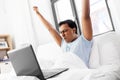 Happy indian man with laptop in bed at home Royalty Free Stock Photo