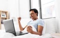 Happy indian man with laptop in bed at home Royalty Free Stock Photo