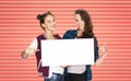 Happy teenage girls or friends holding white board Royalty Free Stock Photo