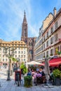 People at the terrace of a brasserie and Notre-Dame cathedral in Strasbourg, France