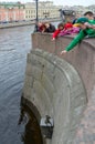 People throw coins on pedestal of Chizhik-Pyzhik monument, St. Petersburg, Russia