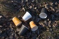 People throw paper coffee cups on ground. The problem of environmental pollution. Pile of abandoned coffee cups on grass in the