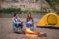 People, tourism and nature concept - Man embrace woman sitting near a fire