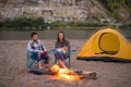 People, tourism and nature concept - Man embrace woman sitting near a fire