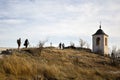 People tourists climb mountain the ancient stone cross and monastery chapel with bell tower. Religion, Christianity.