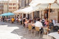 People and tourists eating and drinking on terraces of a Spanish city.