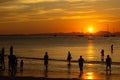 People, tourists enjoy a gorgeous sunset on a tropical beach. Silhouettes of people are all watching the sun. Golden tones. The Royalty Free Stock Photo