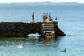 People and tourists are on top of the stone pier of Porto da Barra