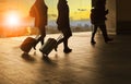 people and traveling luggage walking in airport terminal building with sun set sky at urban scene and air plane flying background Royalty Free Stock Photo