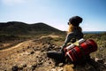 People and trekking backpack travel adventure activity - blonde woman sit down and rest looking at the beautiful scenic landscape