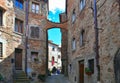 People under arch on the narrow street in old historic alley in the medieval village of Anghiari near city of Arezzo i