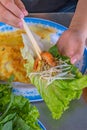 People using chopsticks and wrapping Vietnamese shrimp crepe with lettuce