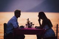 People, vacation, love and romance concept. Young couple enjoying a romantic dinner on beach.