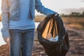 people volunteer keeping garbage plastic and glass bottle into black bag at park river in sunset