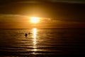 People Wading in Calm Ocean Water at Sunset Royalty Free Stock Photo