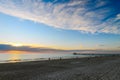 People wailking along the beach at sunset