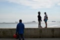 People wait on queue on bay walk to view the artificially face lifted beach coast line dumped with white dolomite sand. silhouette