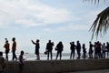 People wait on queue on bay walk to view the artificially face lifted beach coast line dumped with white dolomite sand. silhouette