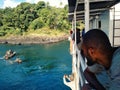 people waiting on a cargo boat next to a stunning tropical island while it uploads with a local outrigger canoe Royalty Free Stock Photo