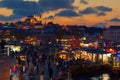People walk along Eminonu Square after sunset. Beautiful night view of Rustem Pasa and Suleymaniye mosques