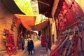 People walk along narrow picturesque street of Fez Medina